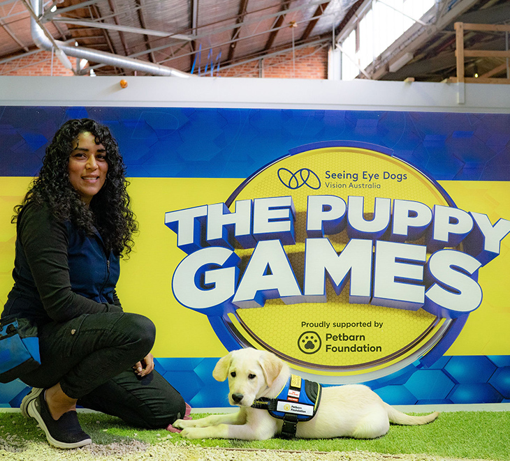 Isobel and trainer Lissette sitting next to Puppy Games sign