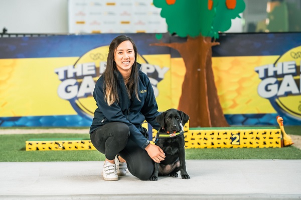 Trainer Lina sits with black Labrador puppy athlete, Rani