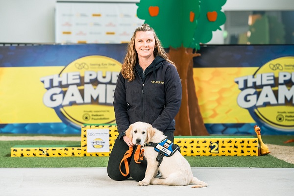 Trainer Paige sits with Golden Retriever puppy athlete, Tom